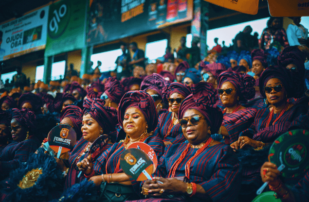 Women in matching navy and maroon aso ebi seated at Ojude Oba