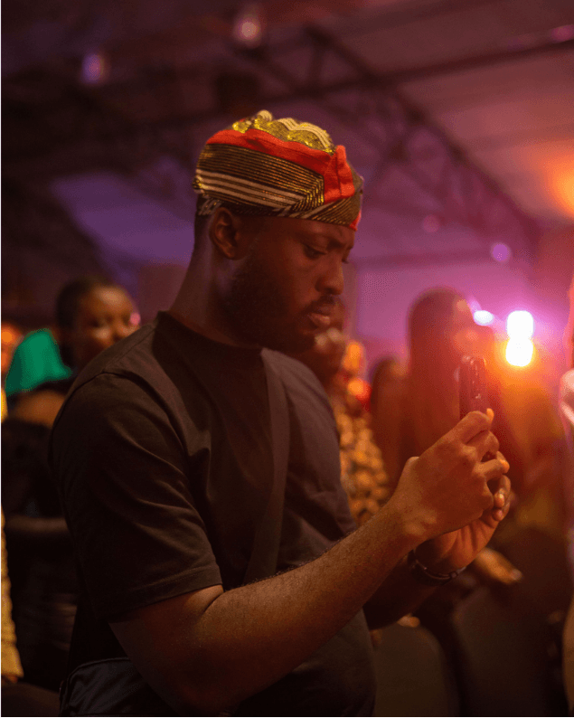 Attendee in traditional cap capturing the moment on his phone