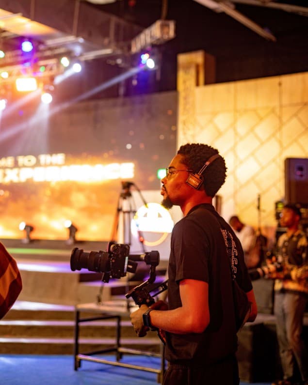 Cameraman filming beside the glowing stage screen
