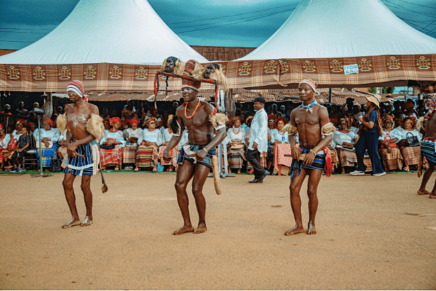 Three dancers performing before the festival tents