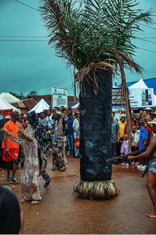 Ceremonial column with palm fronds and leopard-costumed performers