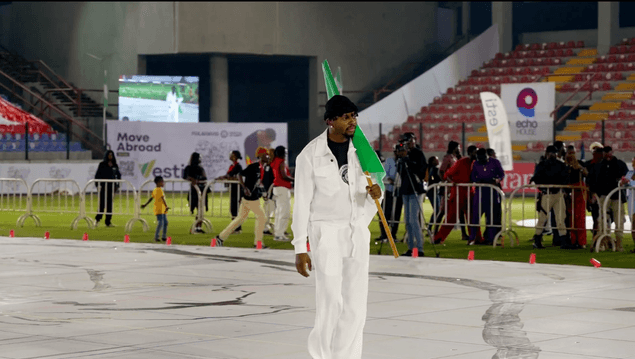 Artist walking the canvas with the Nigerian flag