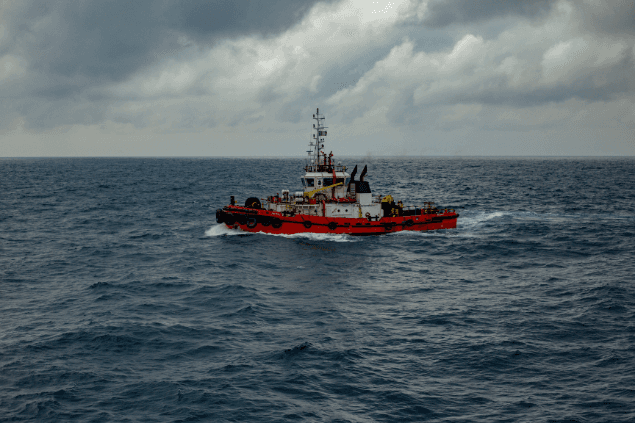Red and white offshore support vessel underway