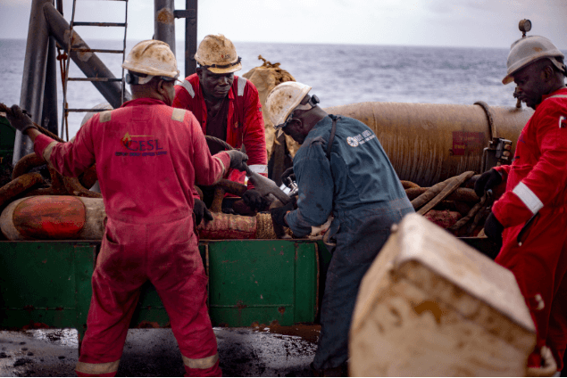 Deck crew working with heavy equipment at sea