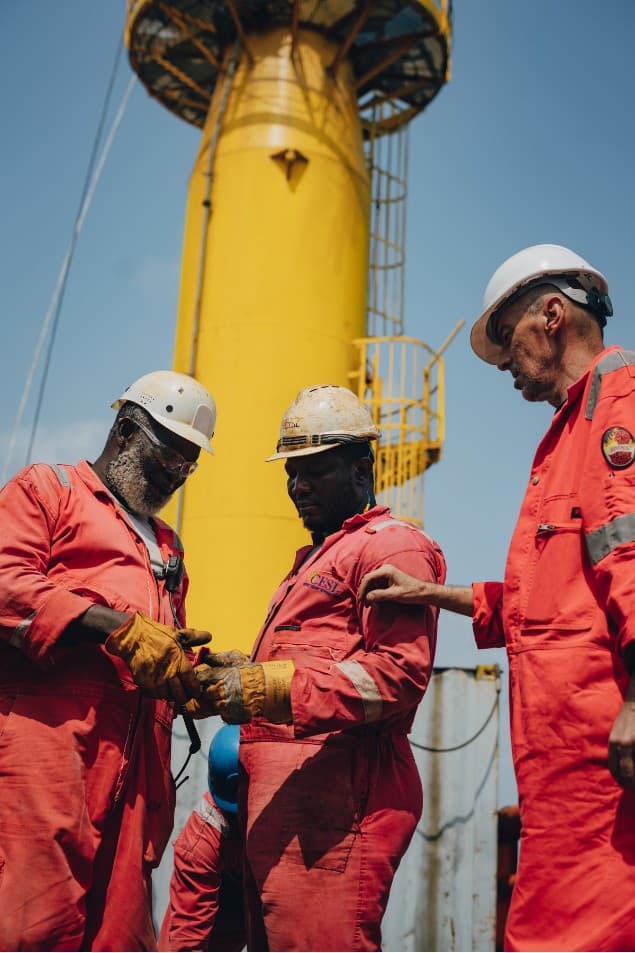 Three workers collaborating on deck under a clear sky