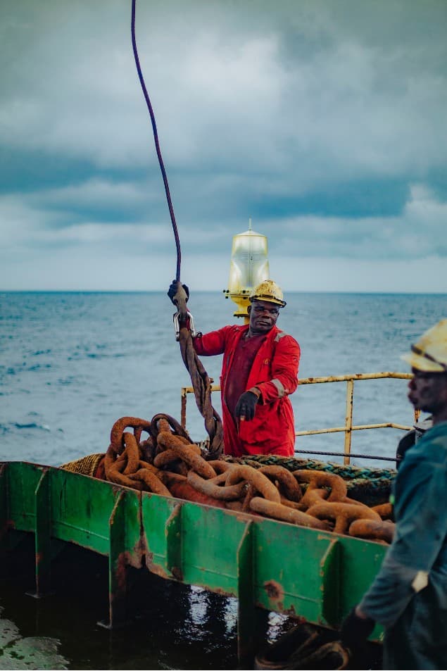 Crew member handling cable above rusted anchor chains