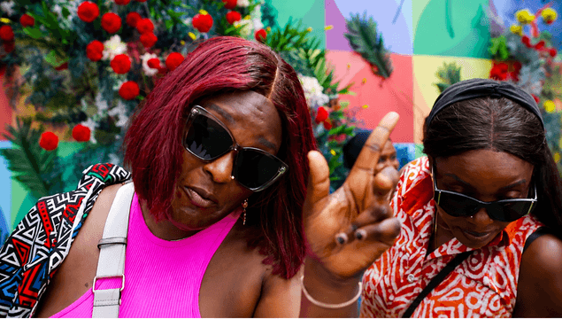 Festival guest in pink top and sunglasses amid carnival flowers