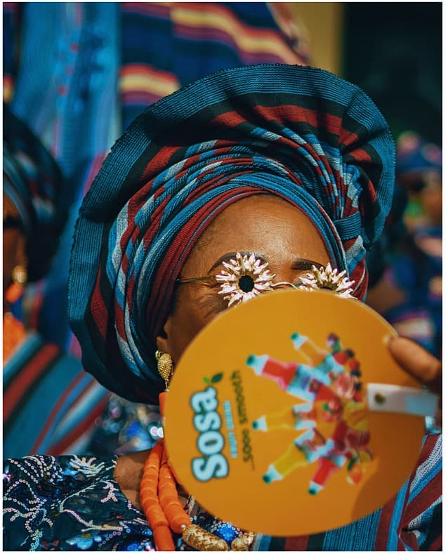 Woman peaking over an orange Sosa hand fan