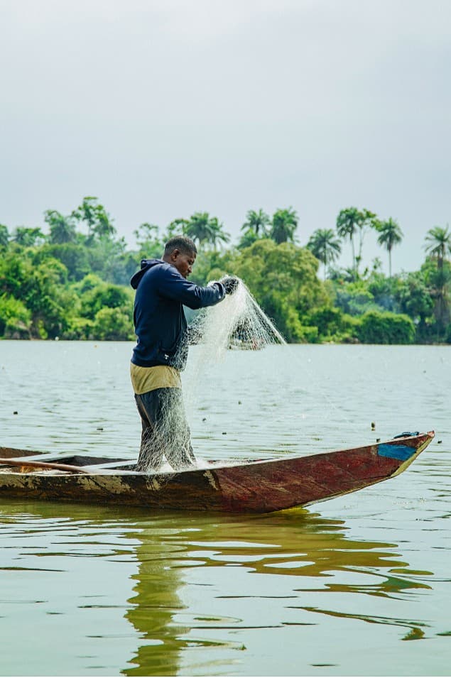 Fisherman casting a white net from a canoe